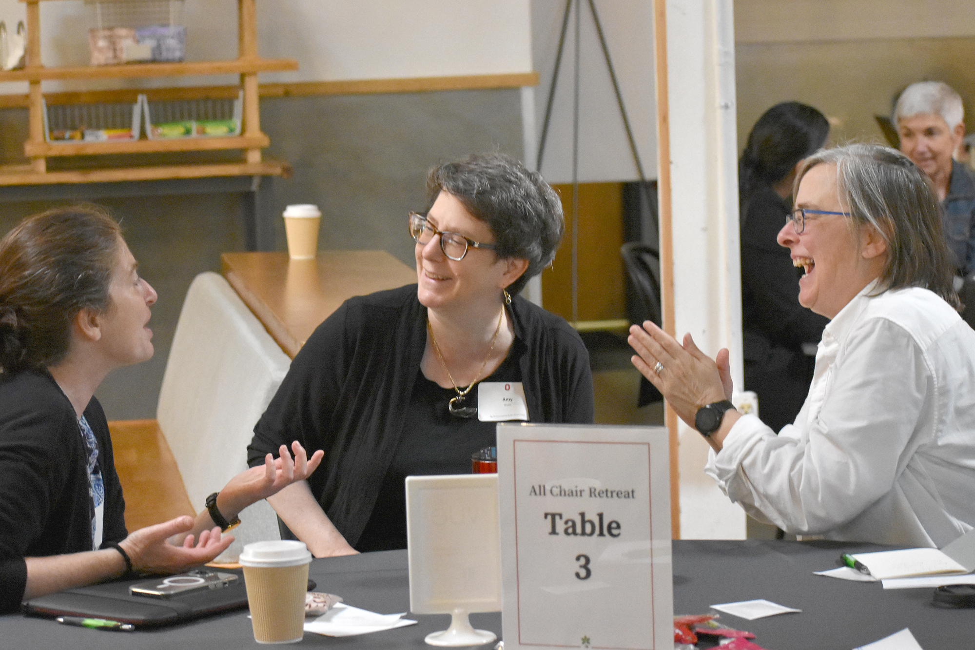 Three people share a laugh while sitting at a table