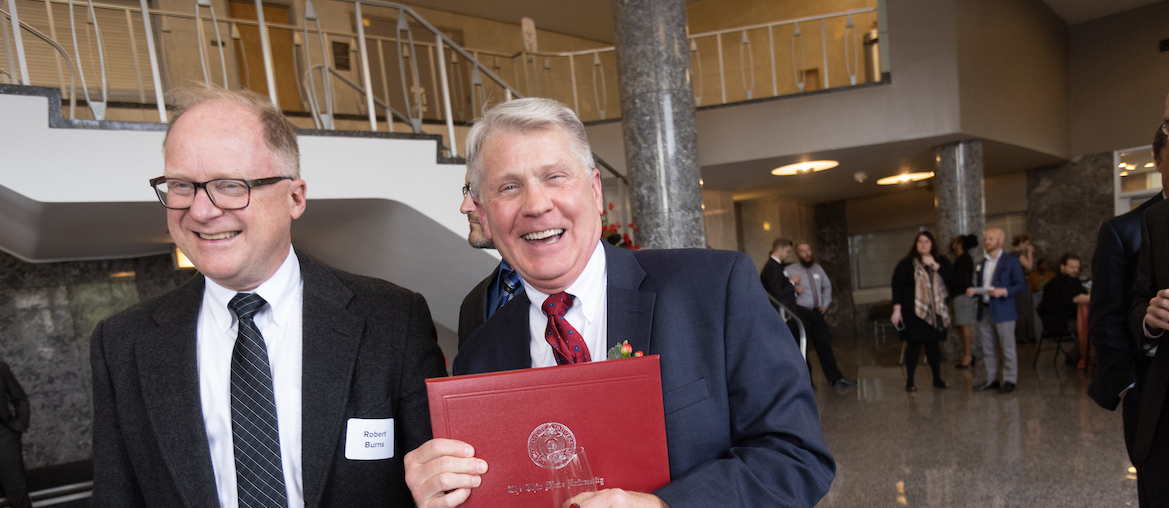 Two faculty members at the Faculty Awards Ceremony. One Faculty Member holds his award certificate.