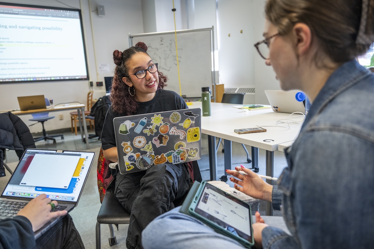 A professor discusses a topic with two students.