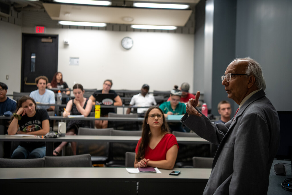 A professor speaks with a class in a medium sized classroom.