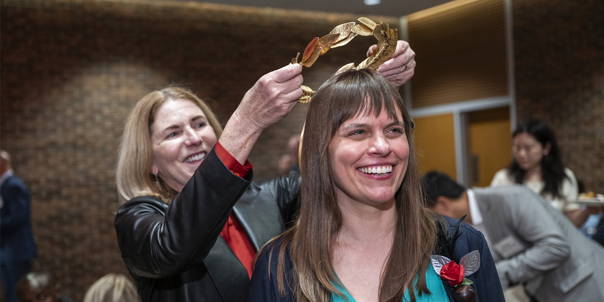 A woman crowns a smiling Kate Shannon with a gilded laurel wreath