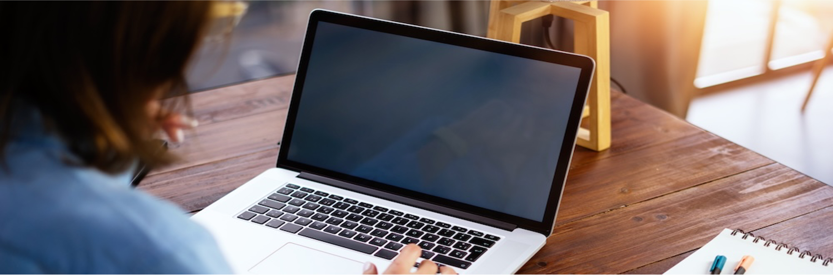 A female sits in front of a silver laptop computer.