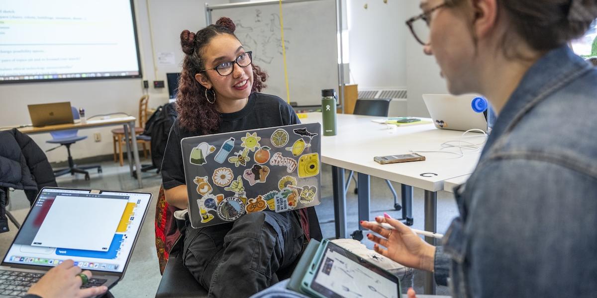 A professor discusses a topic with two students.