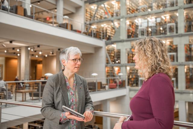 Two staff members talk in the University Library.