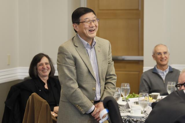 Alan Luo standing at a luncheon table with colleagues