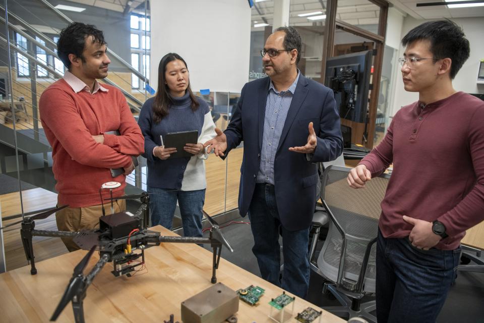 Faculty working with colleagues and students in a drone vehicle lab