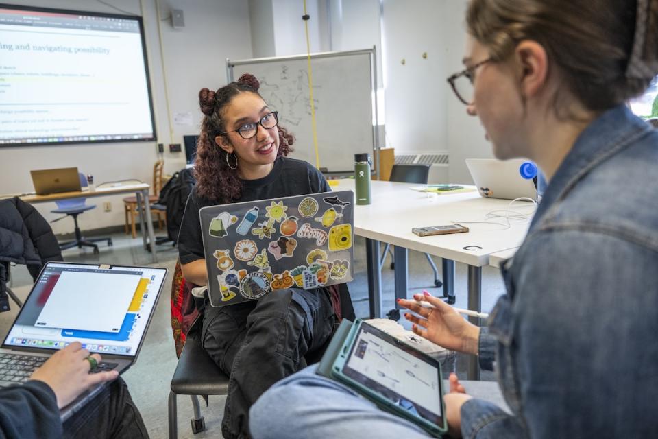 A professor discusses a topic with two students.
