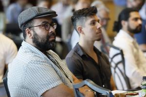 Two young faculty members seated and listening in the audience at the 2023 New Faculty Orientation.